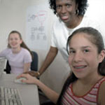 Photo of girls at computer with an adult female. (Photo credit:  Quad Photo/Karineh Gurjian-Angelo/Dedjora Von Jutaz)
