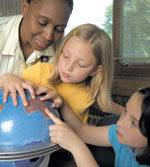 Photo of girls and volunteer looking at a globe. &copy; GSUSA. All rights reserved. (Photographer: Quad Photo/Karineh Gurjian-Angelo/Dedjora Von Jutaz)