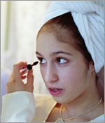Photo of a girl putting on mascara.