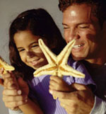 Photo of father and daughter holding starfish.