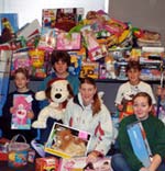 Photo of Girl Scouts in San Francisco posing in front of a pile of gifts.