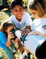 Photo of three Girl Scouts and a telescope.