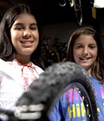 Photo of two girls standing behind a bicycle tire. &copy; GSUSA. All rights reserved.