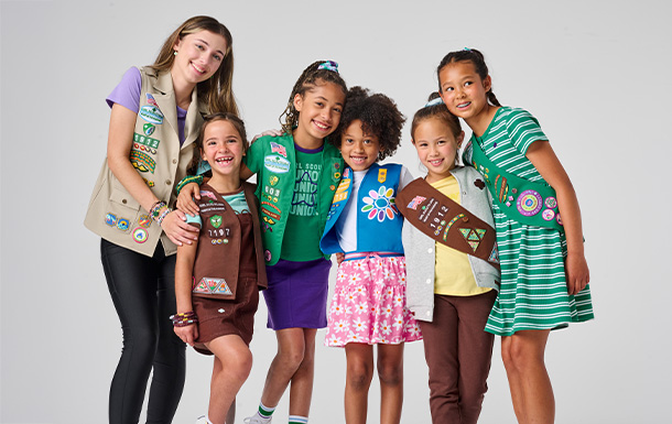 Six Girl Scouts of various ages sitting on a couch together