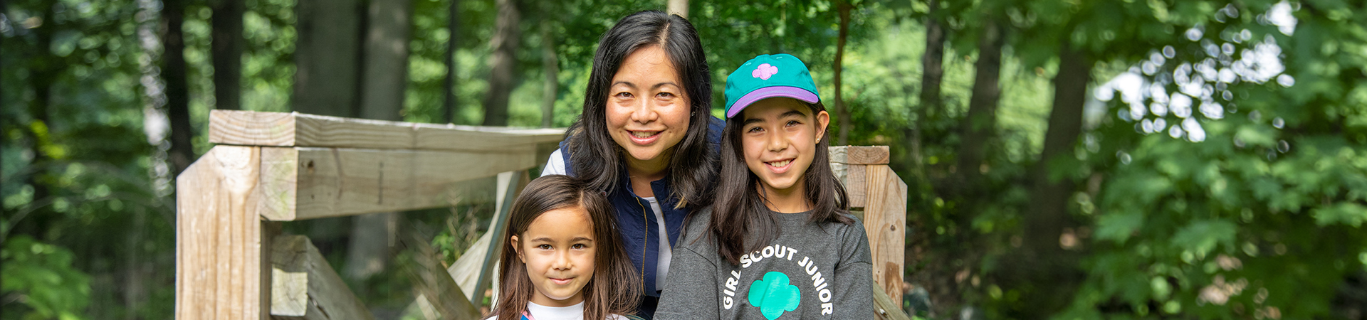  adult volunteer outside with two girl scouts smiling at camera 