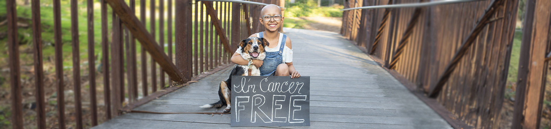  Sarah celebrates with her dog holding a sign saying "I'm cancer free". 
