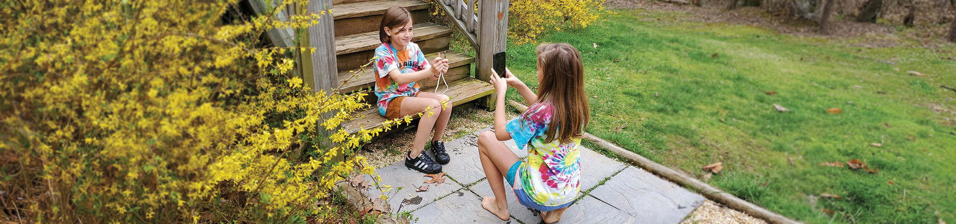  two girls in tie dye shirts filming a video about how to tie a knot 