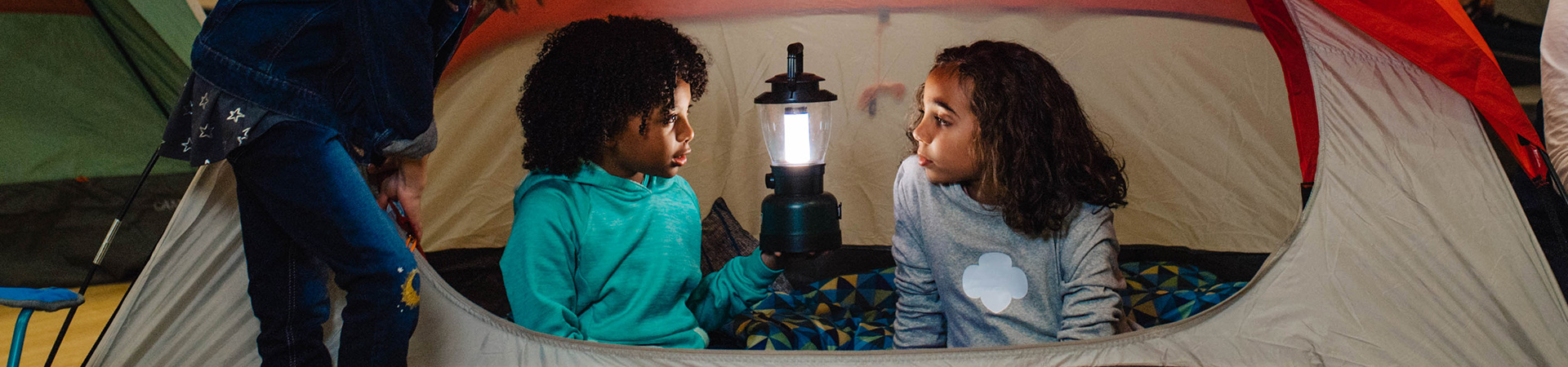  Dos Girl Scouts hablando en una carpa para cámping. 