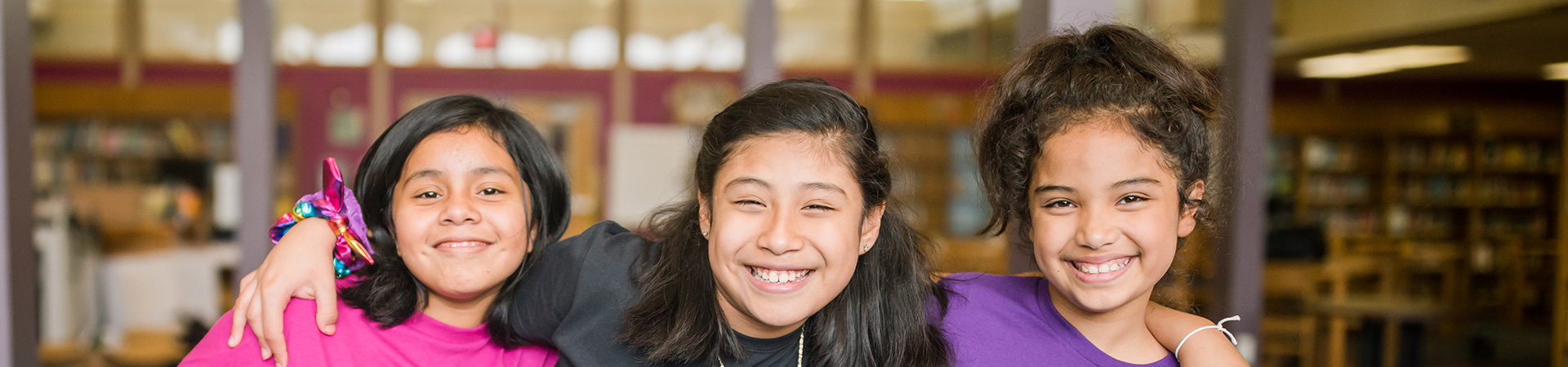  Cuatro Brownie Girl Scouts con los brazos alrededor de los hombros. 